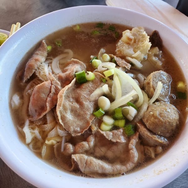 Close-up of a bowl of Boba Pho U pho with beef, meatballs, tripe, onions, and green onions.