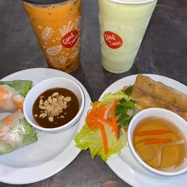 Vietnamese spring rolls, egg rolls, and two Boba Pho U drinks on a dark table.